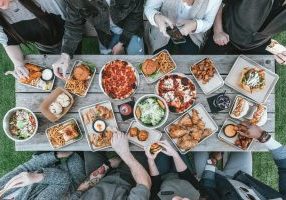 a group of people sitting around a table with food
